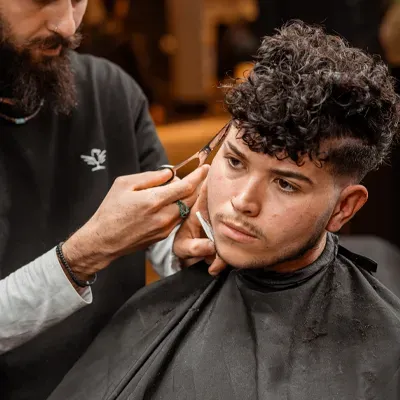 Barber knipt krullend haar met schaar bij City Center Barbershop Amsterdam - Men's curly haircut